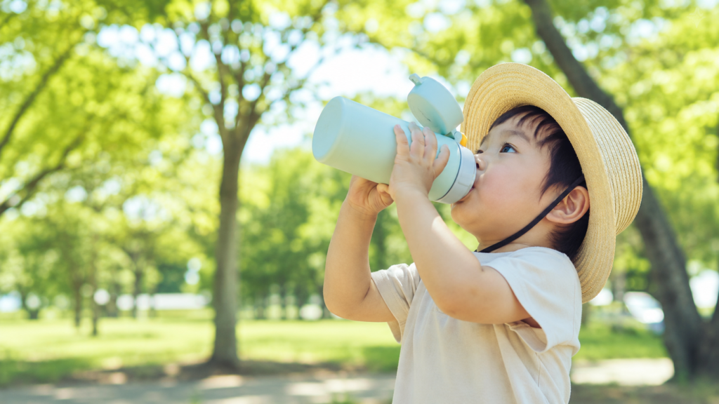 公園で水分補給をする帽子をかぶった子ども