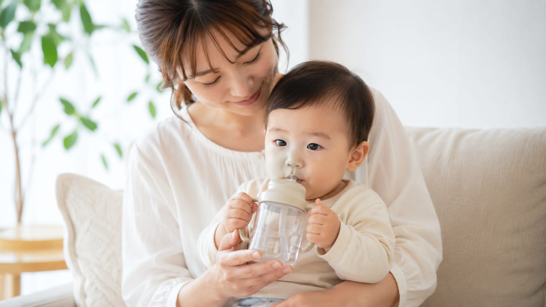 0〜1歳の赤ちゃんがストロー付きマグで水分補給する様子