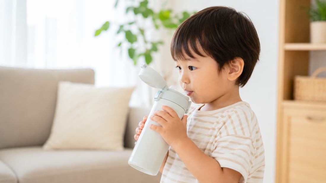 1〜3歳の幼児が自分で水筒を持って飲む練習をする様子