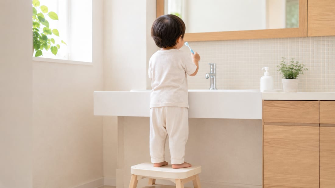 踏み台に乗って自分で歯みがきをする子どもの後ろ姿