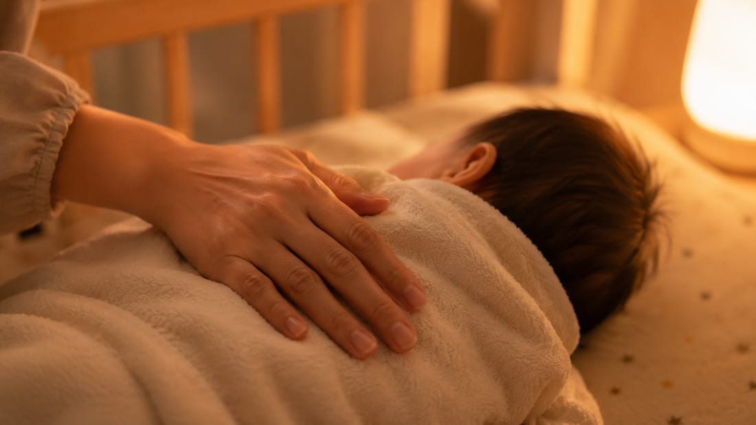 赤ちゃんの背中をやさしくトントンして寝かしつける手
