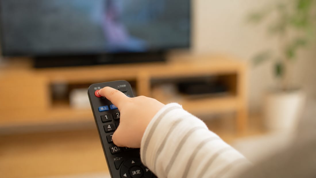 テレビの電源ボタンを自分で押す子どもの小さな手