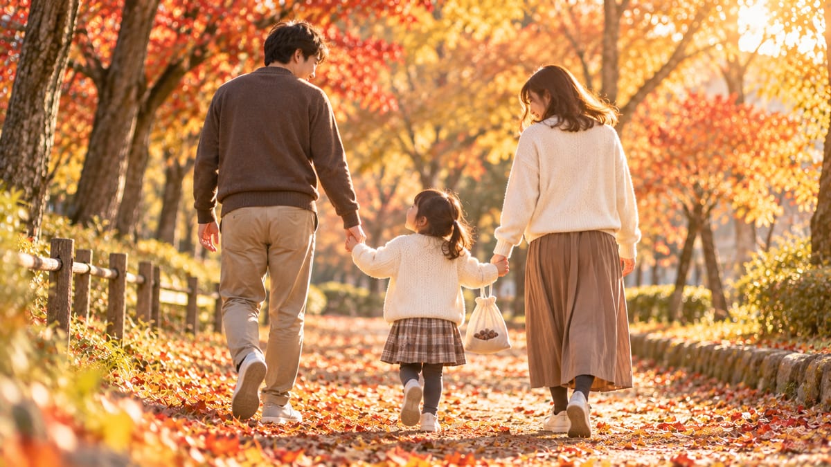 紅葉の並木道を手をつないで歩く親子の後ろ姿